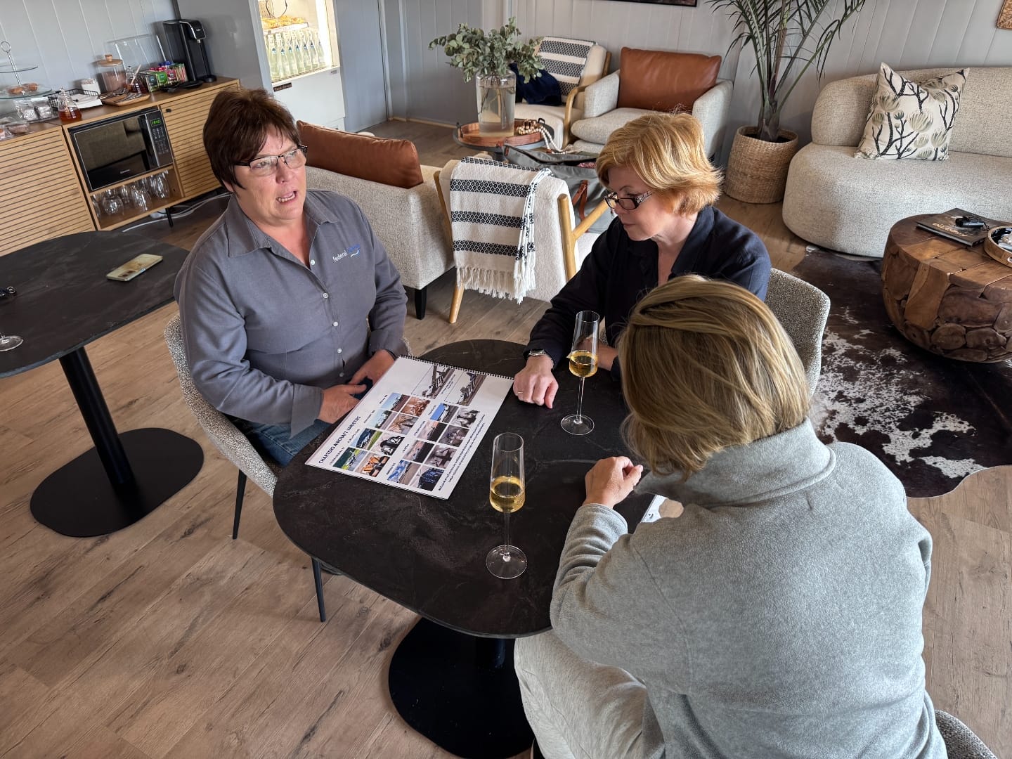 Three women at a table reviewing a Federal Airlines brochure with champagne flutes