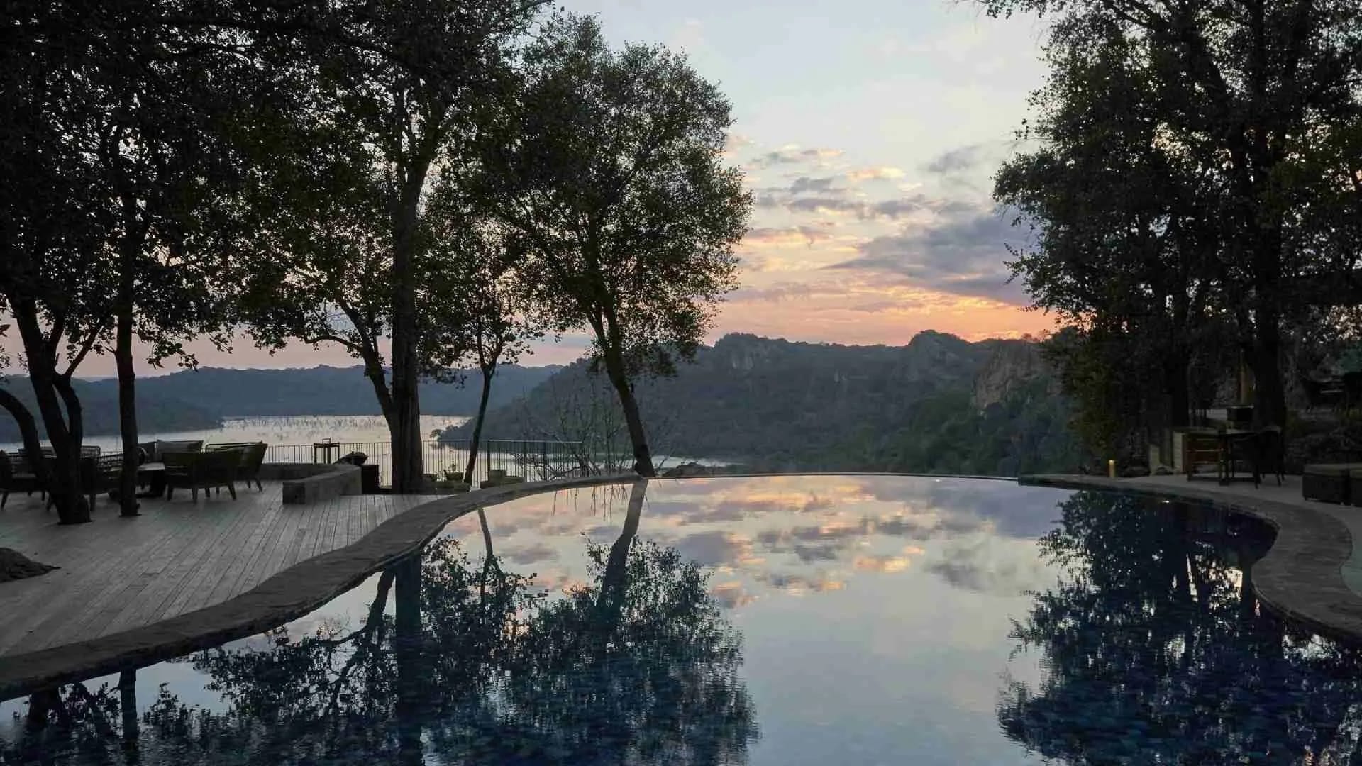 Infinity pool at golden hour with trees framing the view over the gorge, Singita Pamushana, Zimbabwe