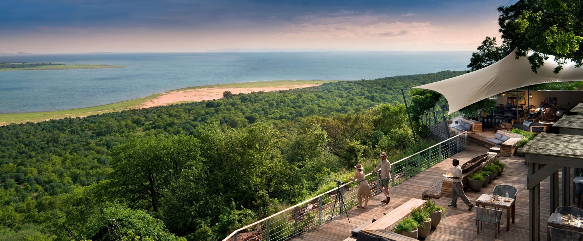 Couple on the viewing deck of Bumi Hills Safari Lodge overlooking Lake Kariba at golden hour