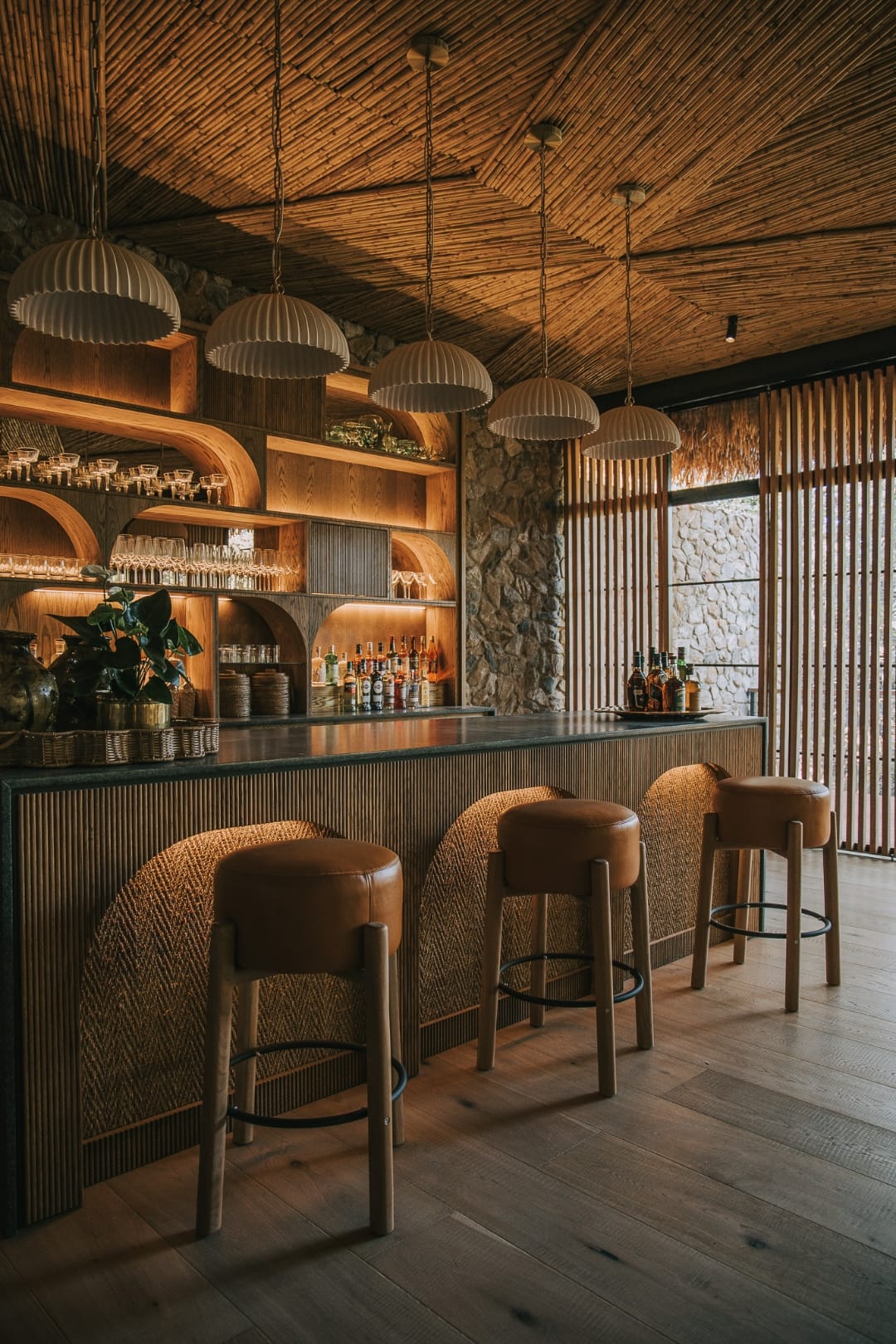 Curved timber bar at Saseka with brass pendant lighting and woven seating