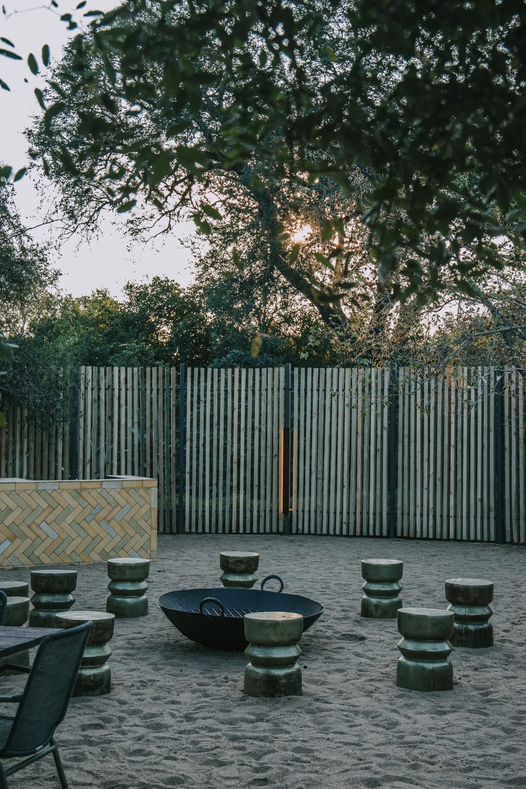 Outdoor boma at Saseka with fire pit, low stools, and open views to the bush