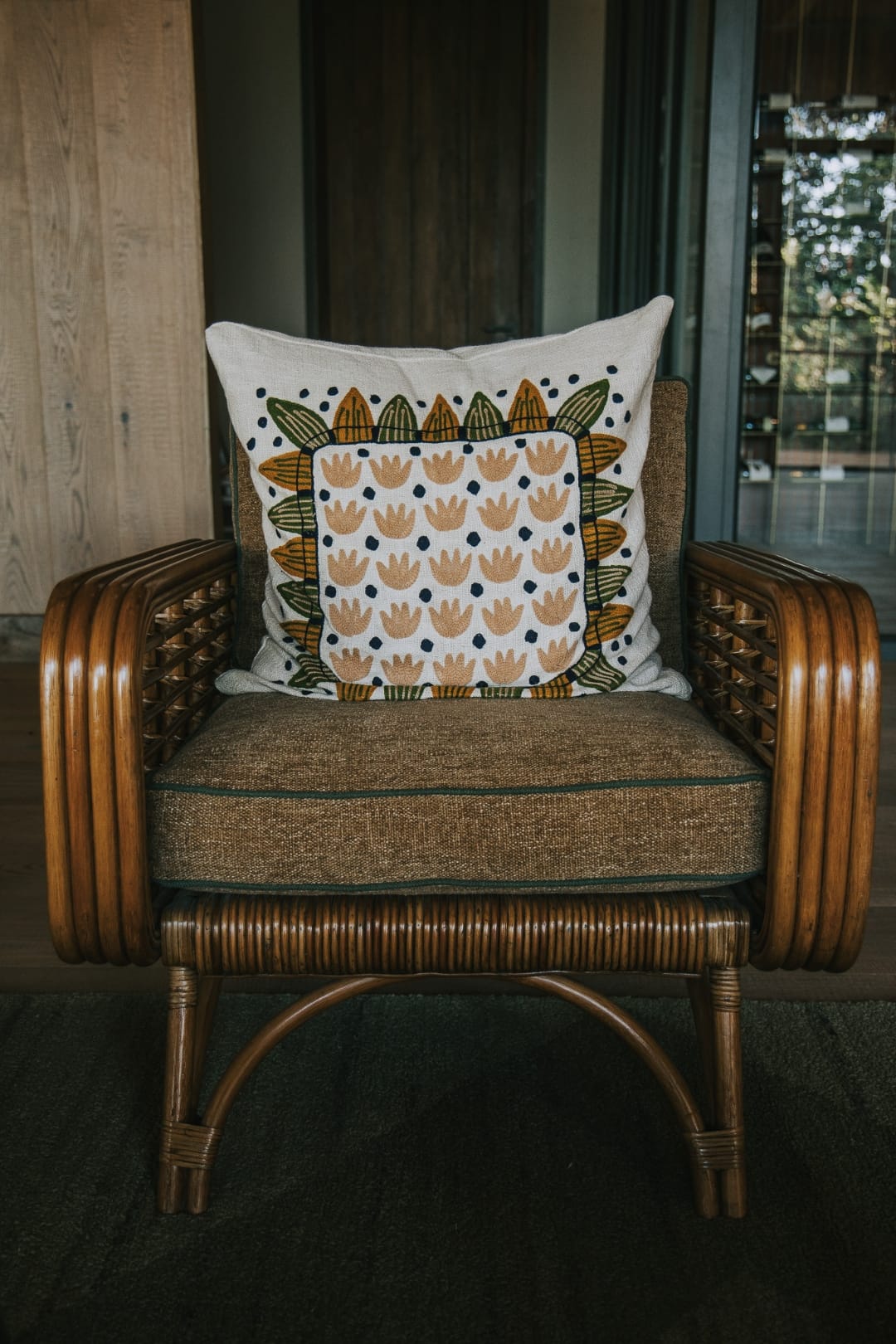 Rattan-backed chair with linen cushion in soft sage and dusty pink tones