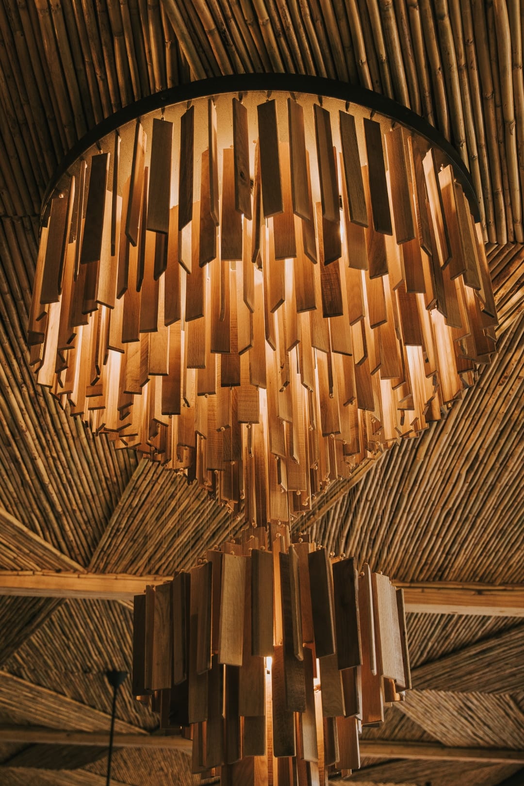 Layered wooden chandelier and geometric ceiling planes above the Saseka lounge