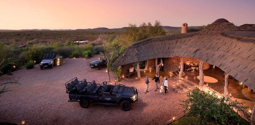 Safari lodge at dusk with game drive vehicles waiting outside, Greater Kruger