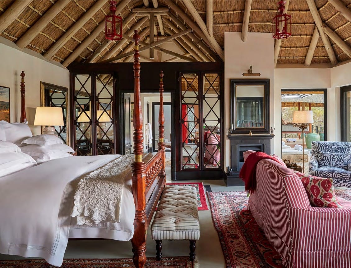 Royal Suite bedroom at Malewane Lodge with four-poster bed, fireplace and doors opening onto the deck.