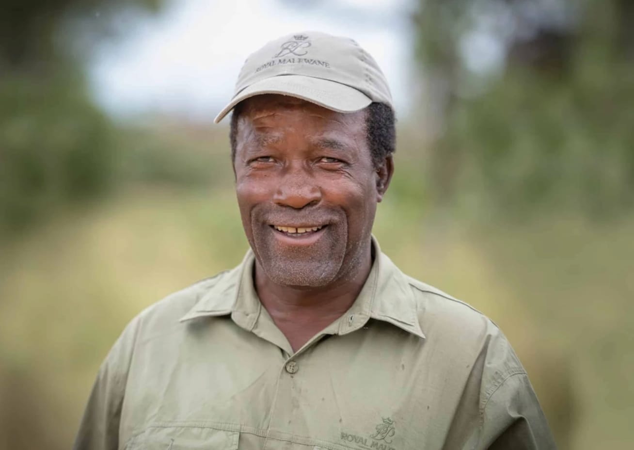 Lucas Mathonsi, Master Tracker at Royal Malewane, smiling in his khaki lodge uniform and cap.