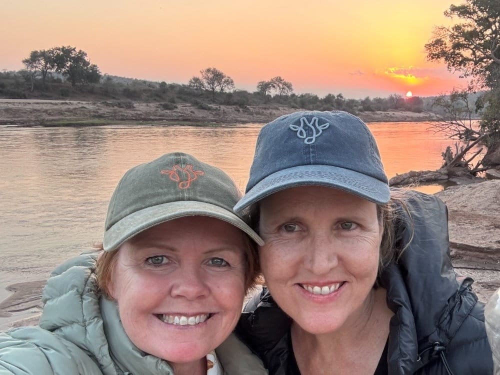 Vikki Jackson and Sian Loehrer on the riverbed wearing Marula Hill caps