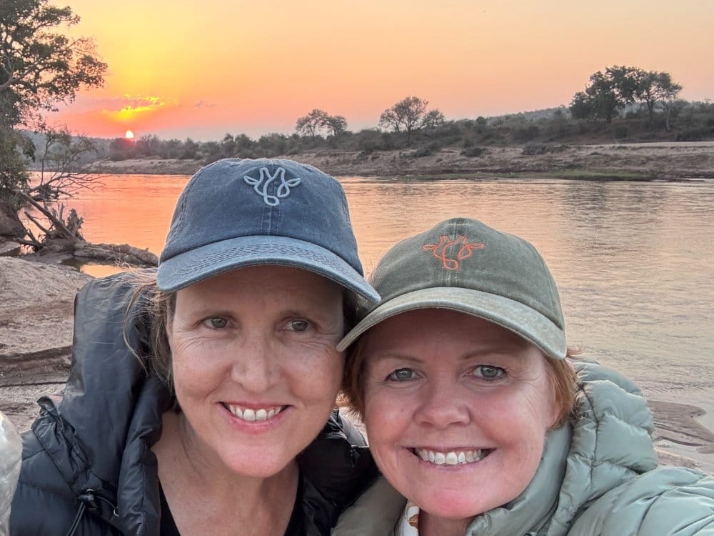 Vikki Jackson and Sian Loehrer on the riverbed wearing Marula Hill caps