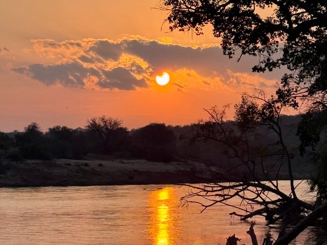 Sunset over the river seen through riverine trees in the Greater Kruger