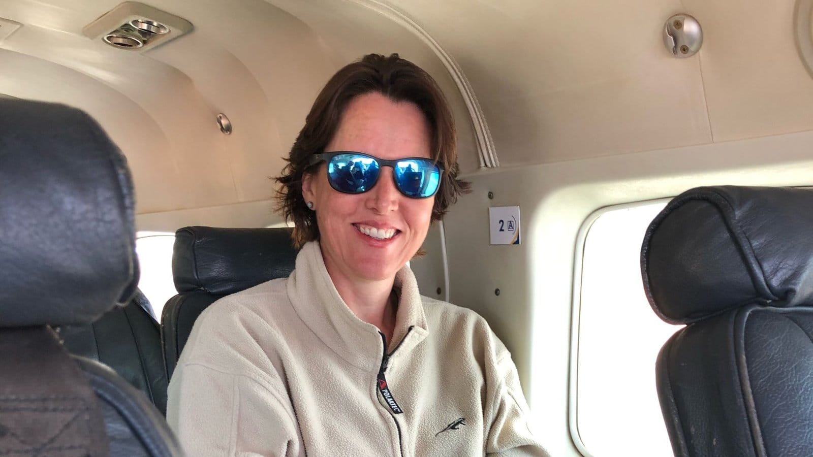 Smiling traveller in sunglasses seated in the cabin of a light aircraft
