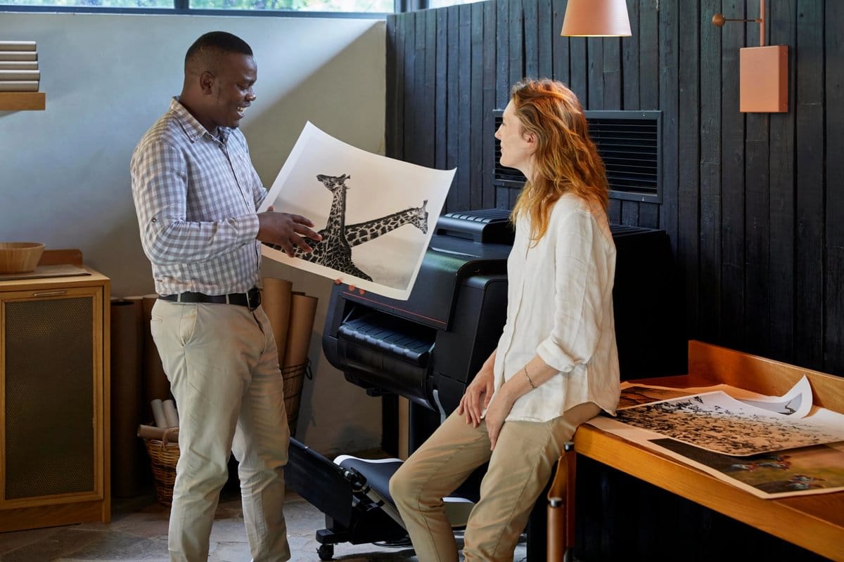 Guide showing a guest a large black-and-white giraffe print in a lodge photography studio