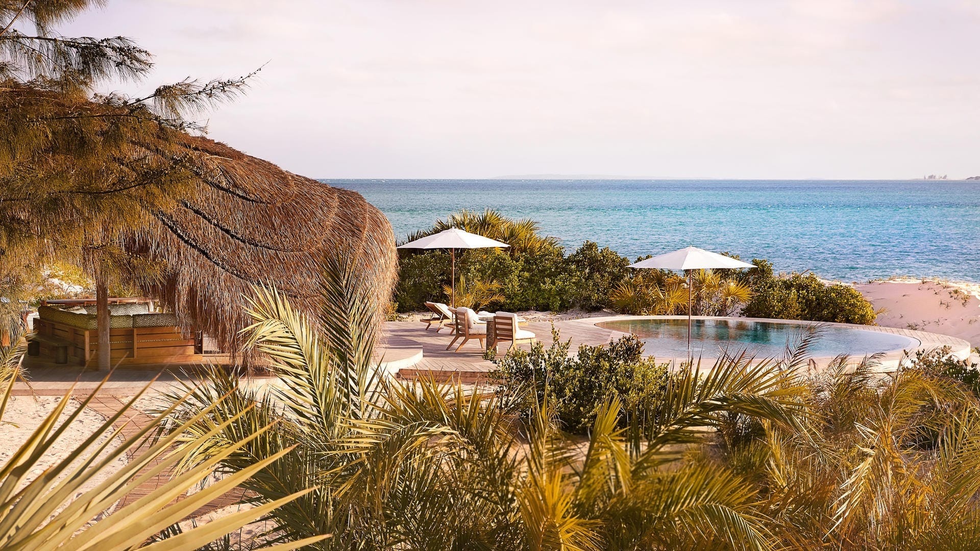 A lodge pool framed by palms with the Indian Ocean beyond, Benguerra Island, Mozambique