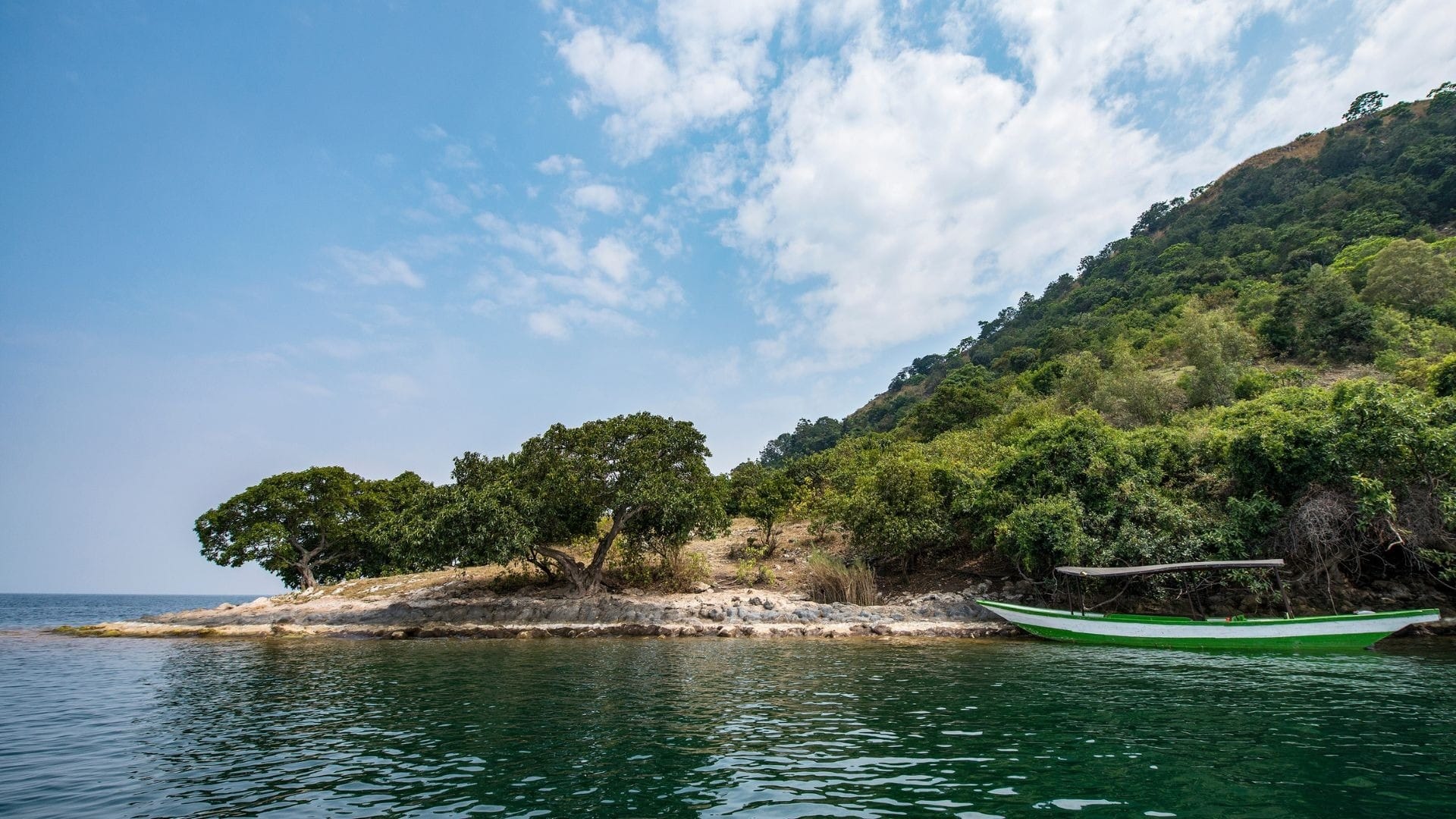 Wooden boat moored off a wooded shoreline on Lake Kivu, western Rwanda