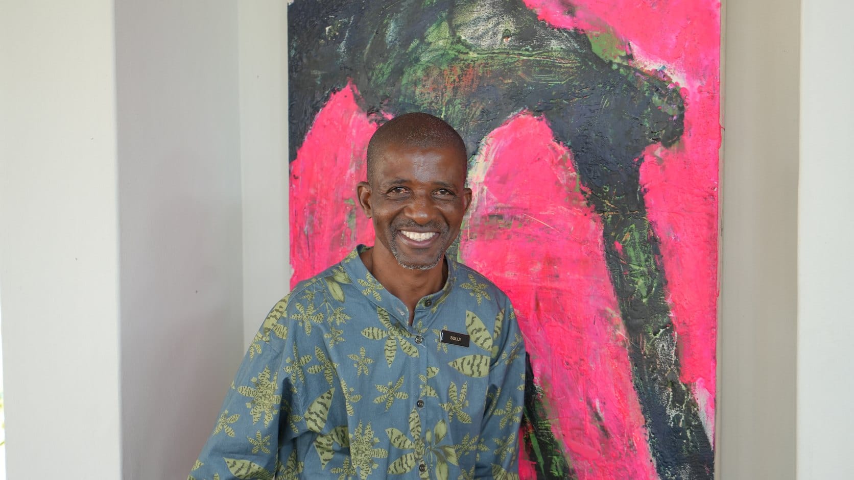 Solly, a member of the lodge team, in the dining room in front of a pink and green abstract painting