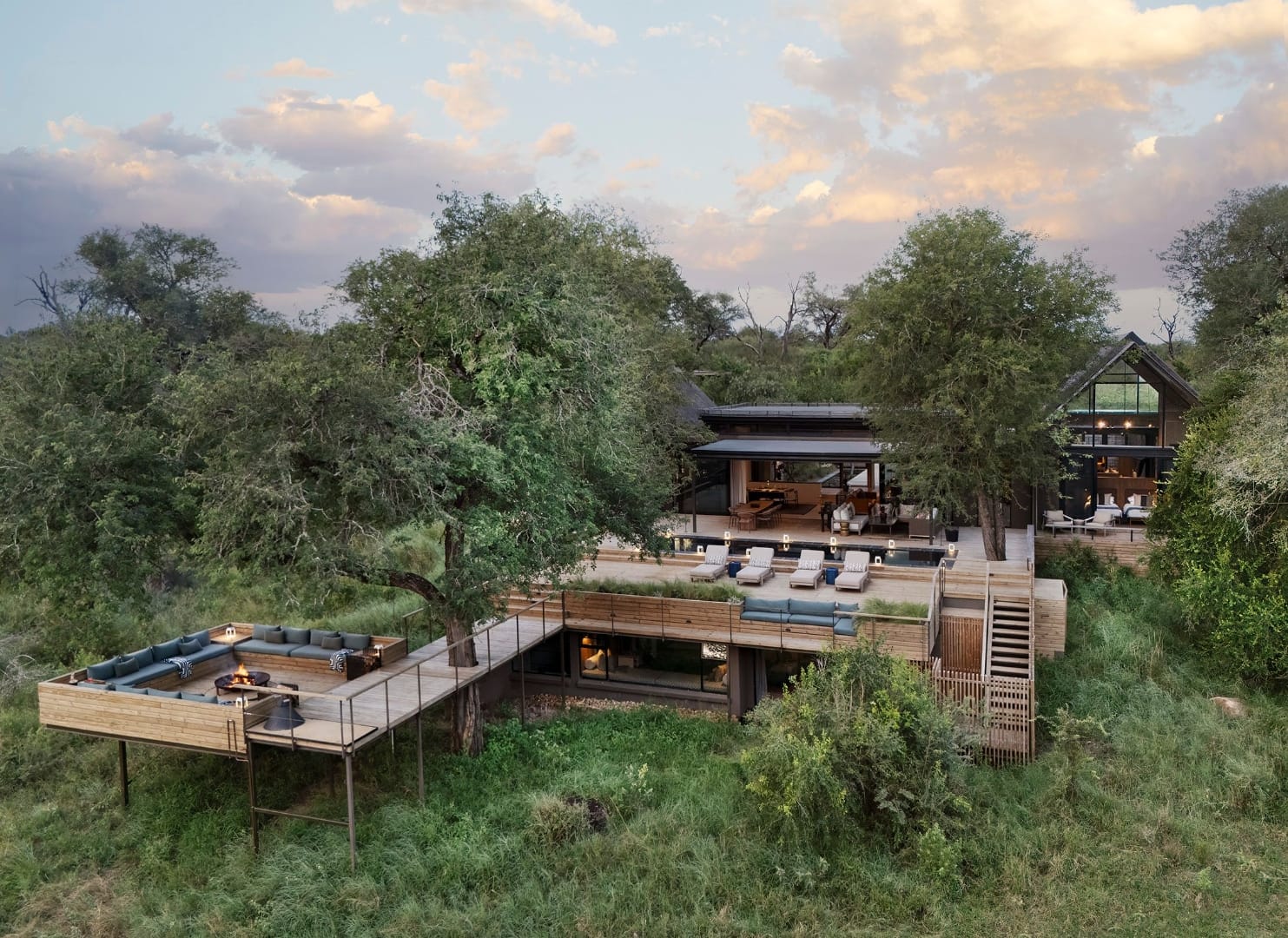 Lion Sands Fish Eagle Villa at dusk, timber decks and a fire pit set above the bush
