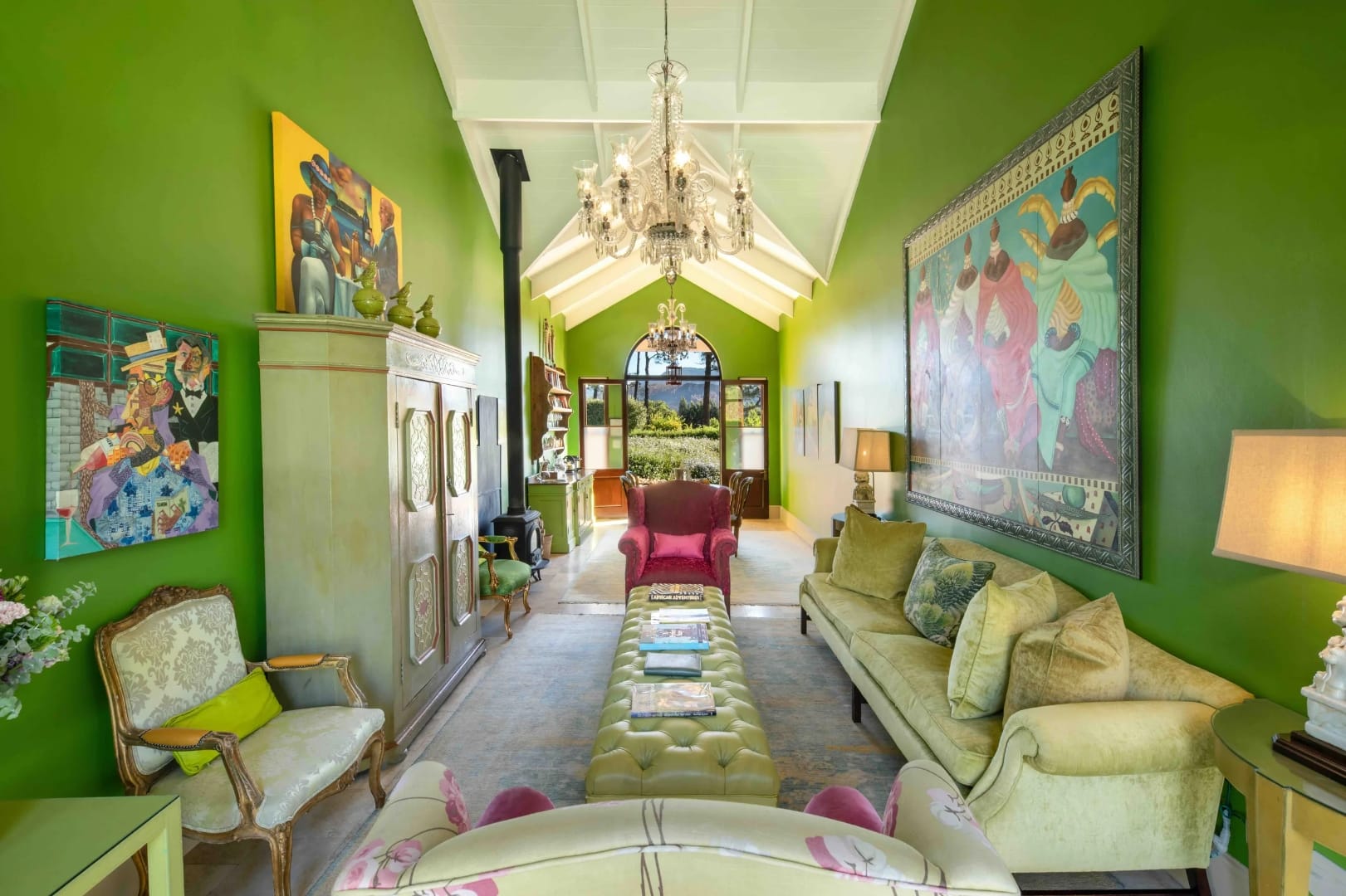 Green drawing room in a Cape Winelands house, with art, a chandelier and doors open to the garden
