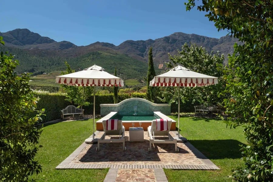 Garden pool with striped umbrellas and loungers beneath the mountains of the Cape Winelands
