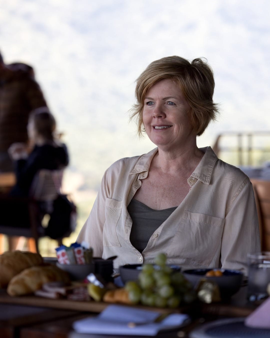 Vikki Jackson at the breakfast table after a morning game drive, light on the hillside behind her