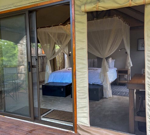 Looking into a tent from the veranda, bed under a mosquito net