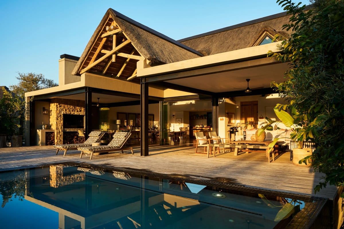 Thatched private villa with an open-sided lounge and pool deck in golden evening light