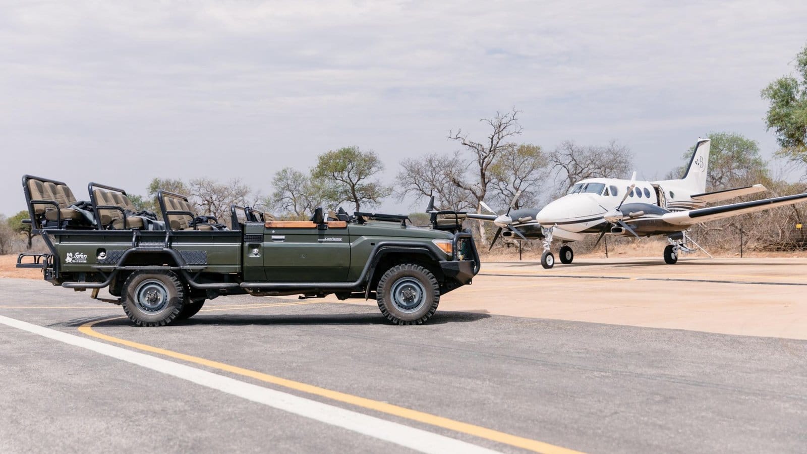 Open safari vehicle waiting beside a light aircraft on a bush airstrip