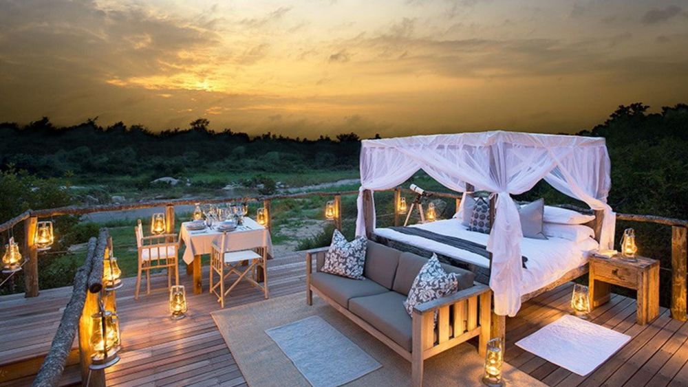 Couple watching sunset over the South African bushveld from a luxury safari lodge deck