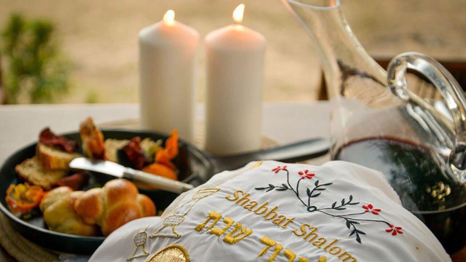 Sabbath candles and challah on a private safari lodge dining table at sunset