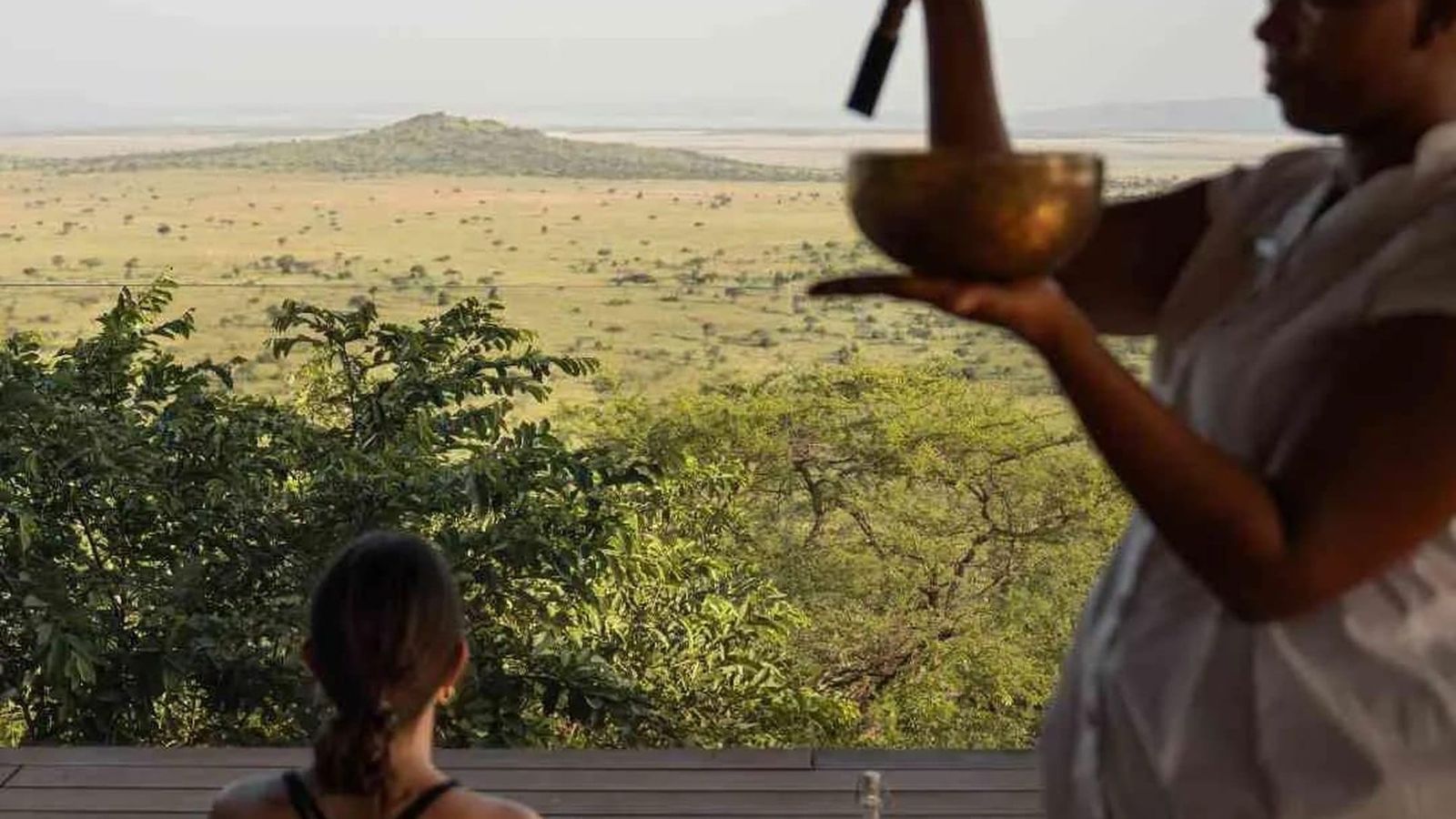 Outdoor yoga deck at a luxury safari lodge overlooking an African floodplain at dawn