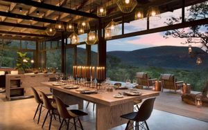 Lantern-lit outdoor dinner table set in the African bush at dusk