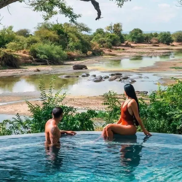 A couple on a private deck at a safari lodge at sunset