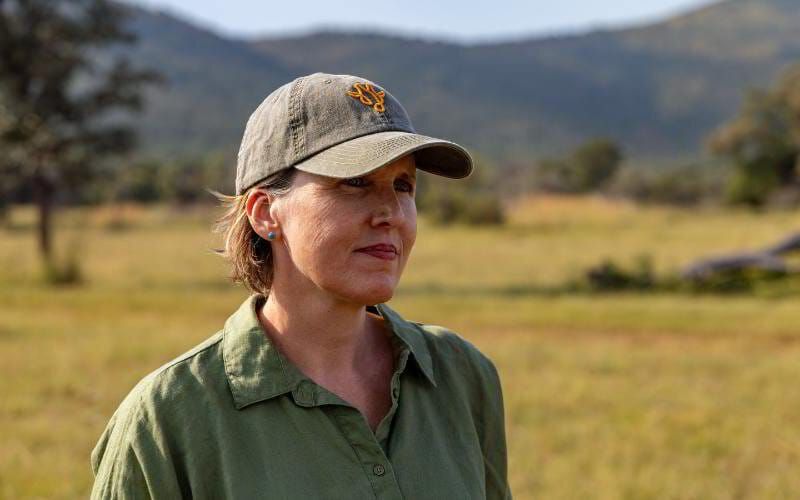 Sian Loehrer of Marula Hill Travel standing in the African bush, wearing a safari cap and green shirt—embodying the personalised, expert-led approach behind every tailor-made safari.