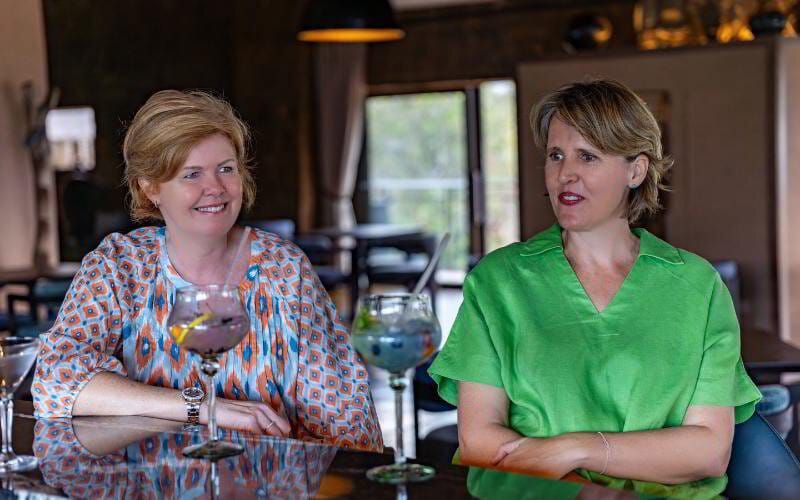 Sian Loehrer and Vikki Jackson of Marula Hill Travel enjoying a relaxed conversation over cocktails—reflecting their personal, approachable style in crafting tailor-made African safaris.