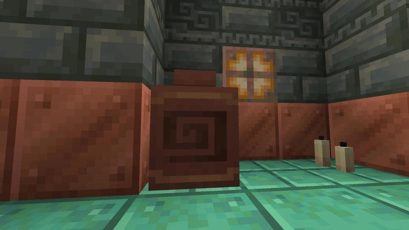 Decorated pot inside a Trial Chamber room, surrounded by copper floor tiles, tuff bricks, and two candles.