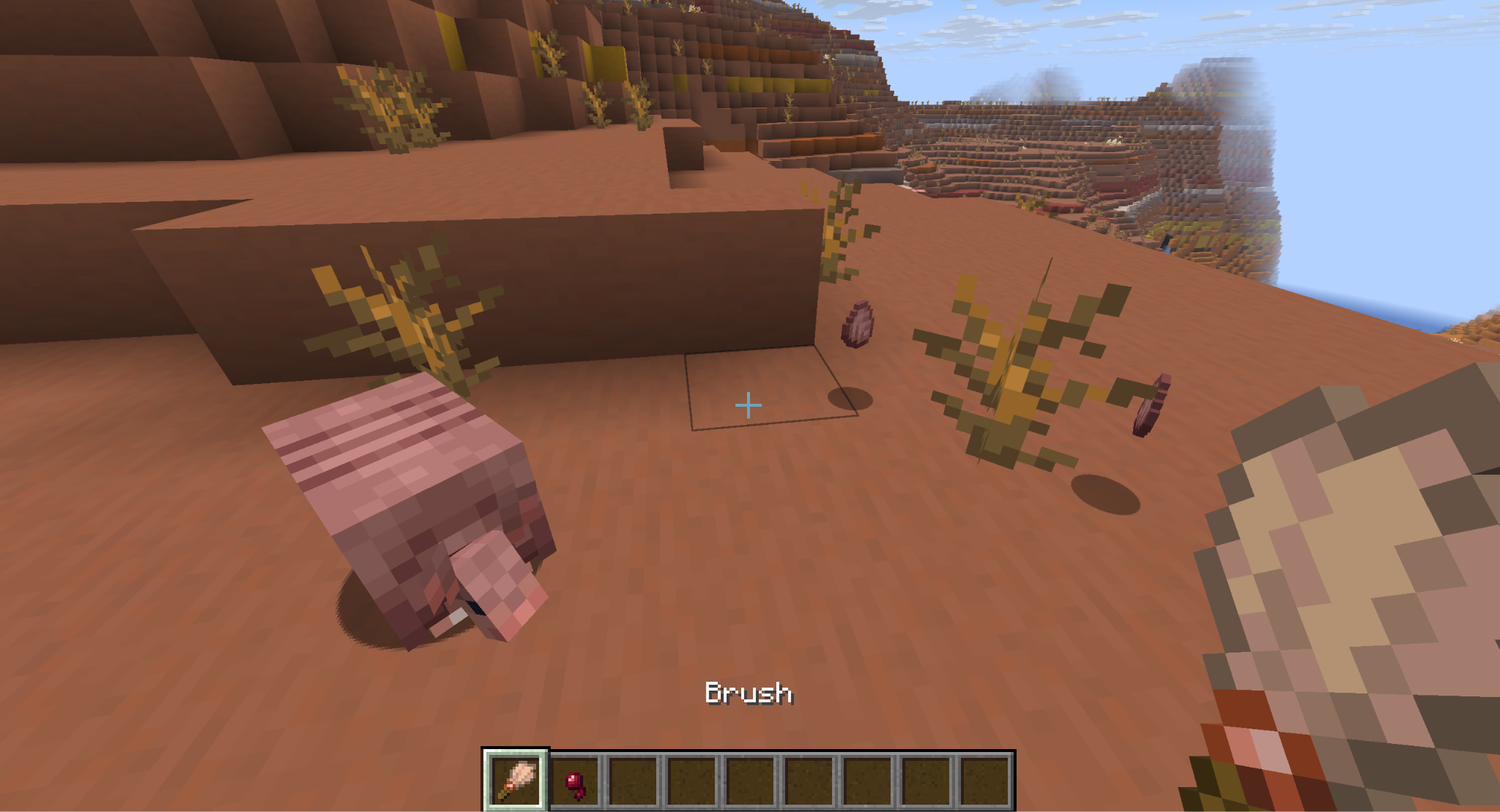 A Minecraft screenshot of an armadillo near a player holding a brush and some loose scutes.