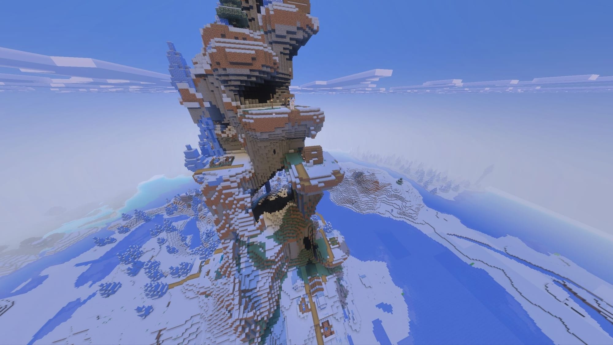 A Minecraft screenshot of a village on layers of a tall narrow mountain.
