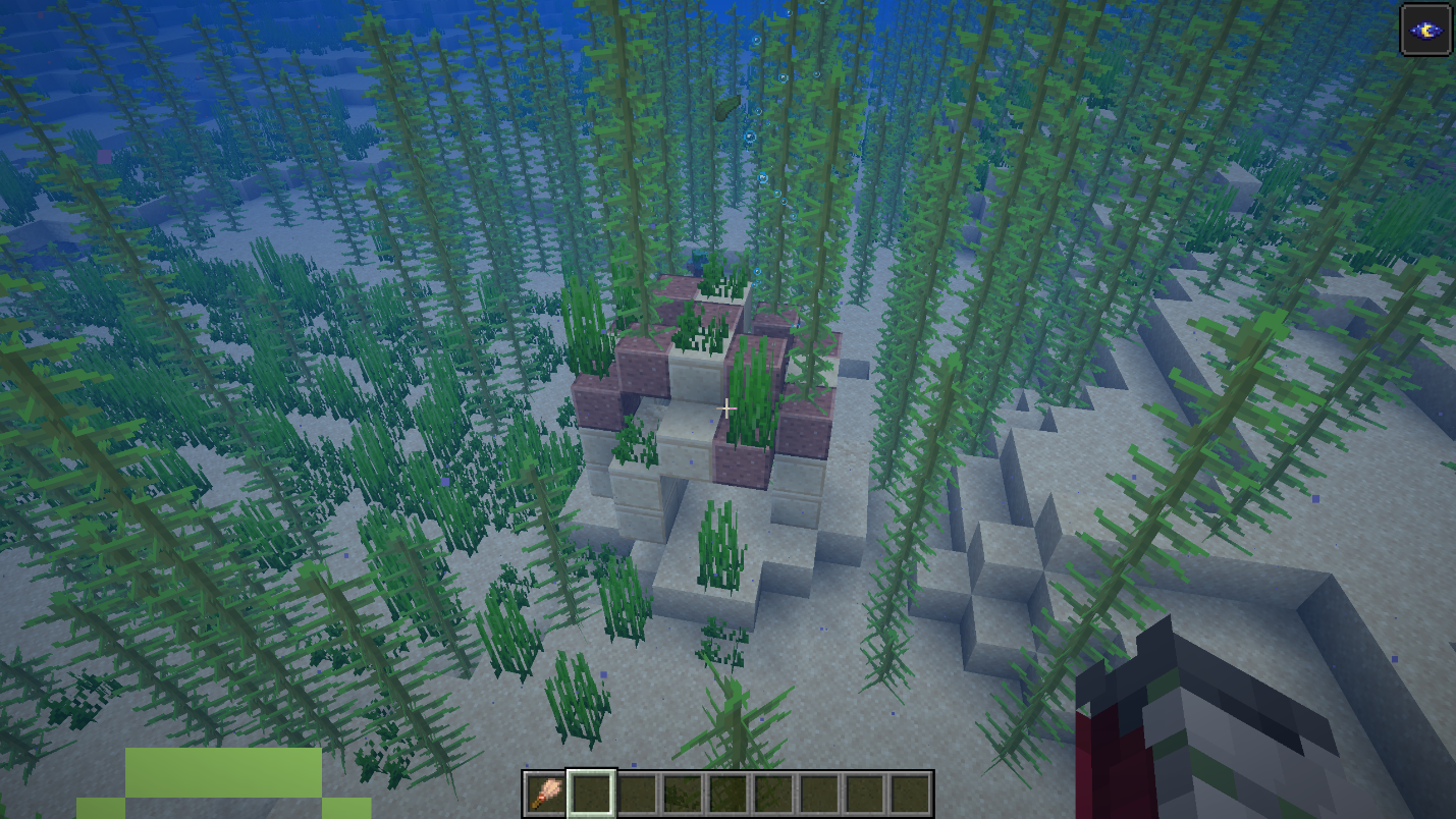 An underwater warm ocean ruin made of sandstone blocks, partially covered in kelp and seagrass.