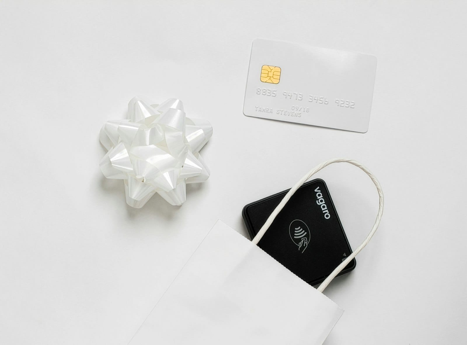 A gift card next to a decorative bow and a gift bag on a white surface