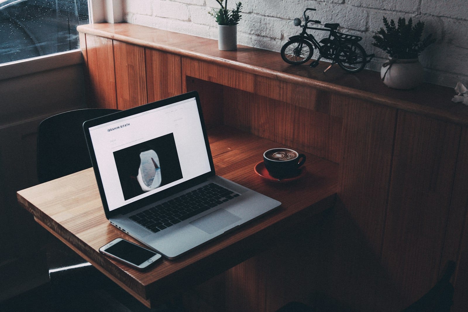 A writer working on a laptop at a wooden desk with a coffee cup