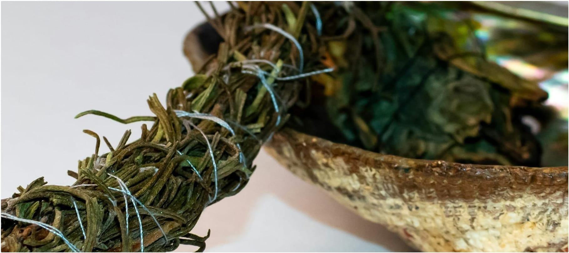 Close up of an abalone shell and a bundle of sacred medicine.