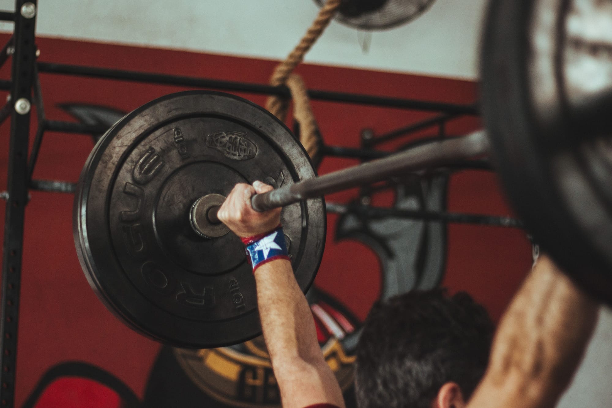 A man holds a barbell above his head