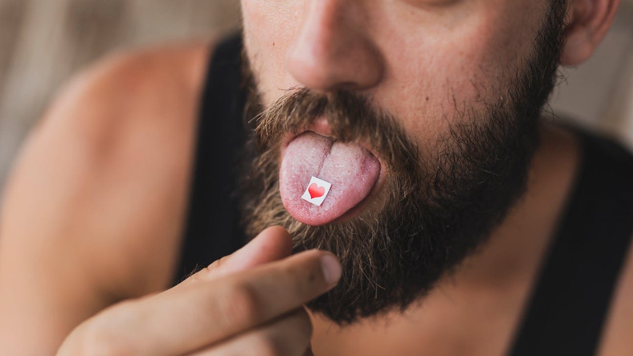 A man puts a tab of LSD on his tongue