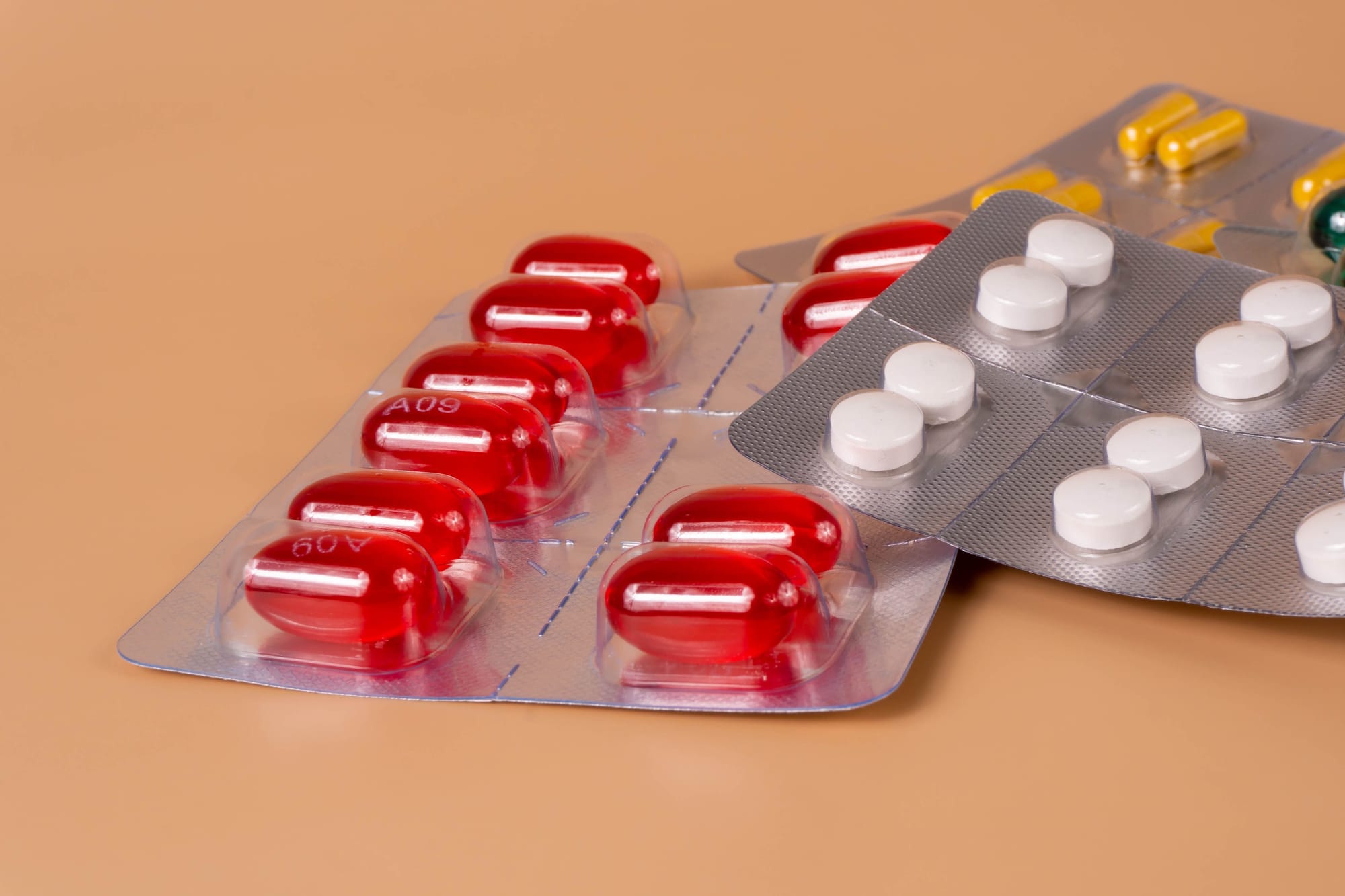 An image of two medication packets. One is red capsules, the other is white pills