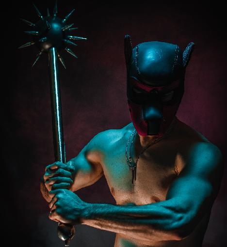 A man in a puppy-play mask wields a morning star