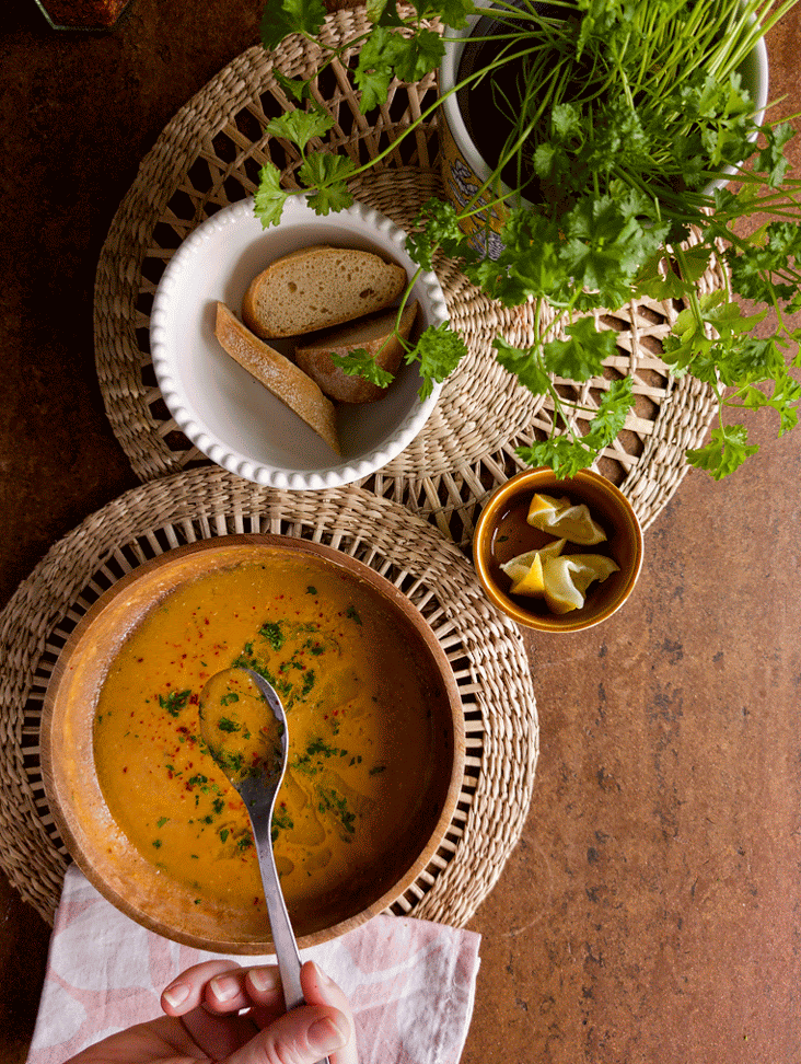 Schale mit Brot gereicht zu einem Teller Türkischer Linsensuppe, serviert mit Zitrone