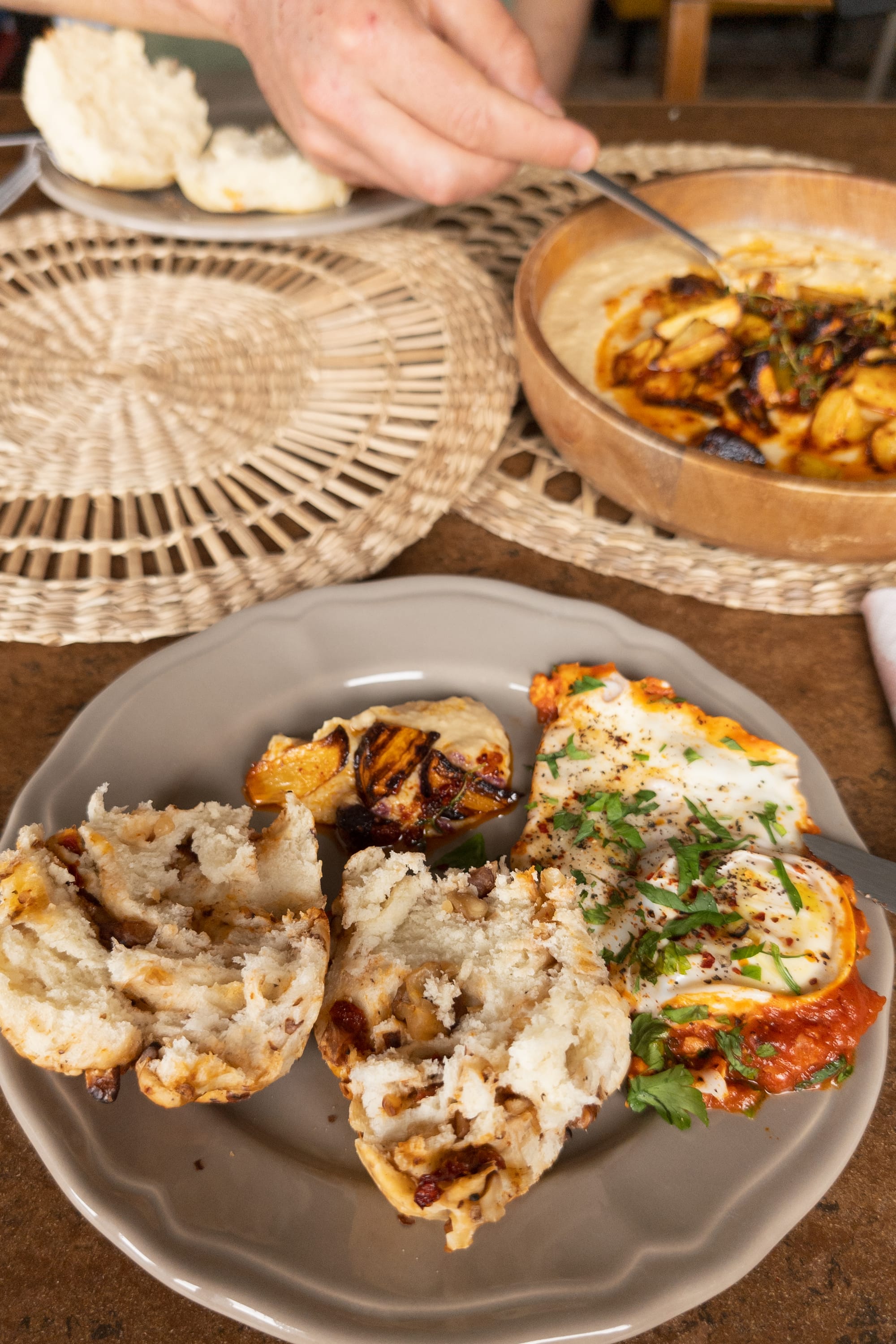 Teller mit selbstgebackenen Dinkel-Walnuss-Tomaten-Brötchen, tomatisierte Eier und Hummus mit Wurzelgemüse