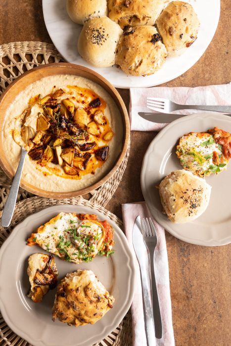 Selbstgebackene Dinkelbrötchen, Eier auf Tomatensoße und pikanter Hummus mit Wurzelgemüse