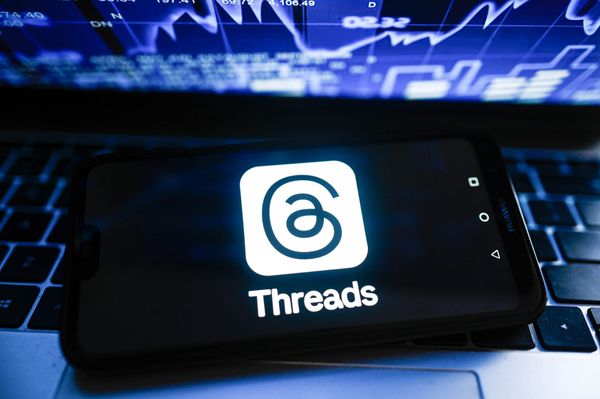 In this photo illustration a Threads logo is displayed on a smartphone with stock market percentages in the background