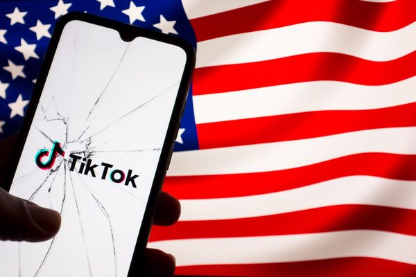 TikTok splash screen on a broken phone against the backdrop of an American flag.