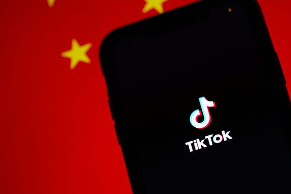 TikTok's splash screen on a mobile phone held against a Chinese flag