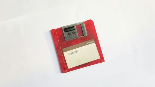 The disk is red against a white background. 12/11/03 is written on the front of the disk in pen